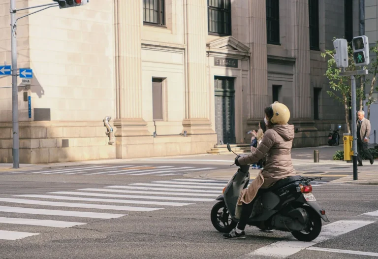 Casco jet per la città: motociclista con casco jet su uno scooter a un incrocio