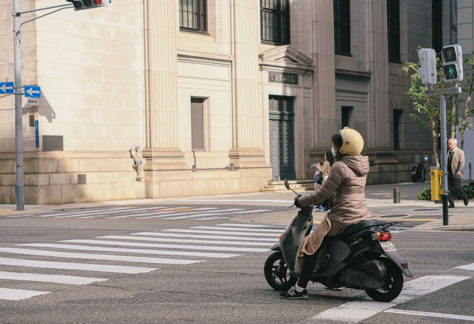 Casco jet per la città: motociclista con casco jet su uno scooter a un incrocio
