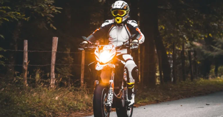 Gilet airbag moto: motociclista con abbigliamento protettivo completo su una strada nel bosco