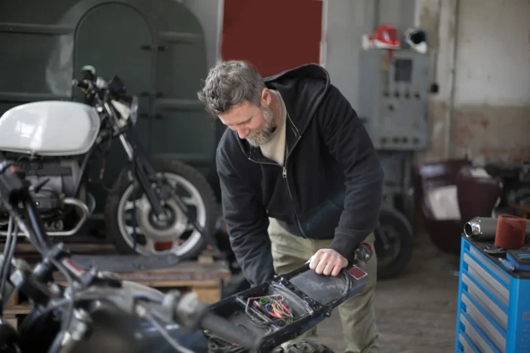 Mantenitore batteria moto: meccanico al lavoro sull'impianto elettrico di una moto in garage